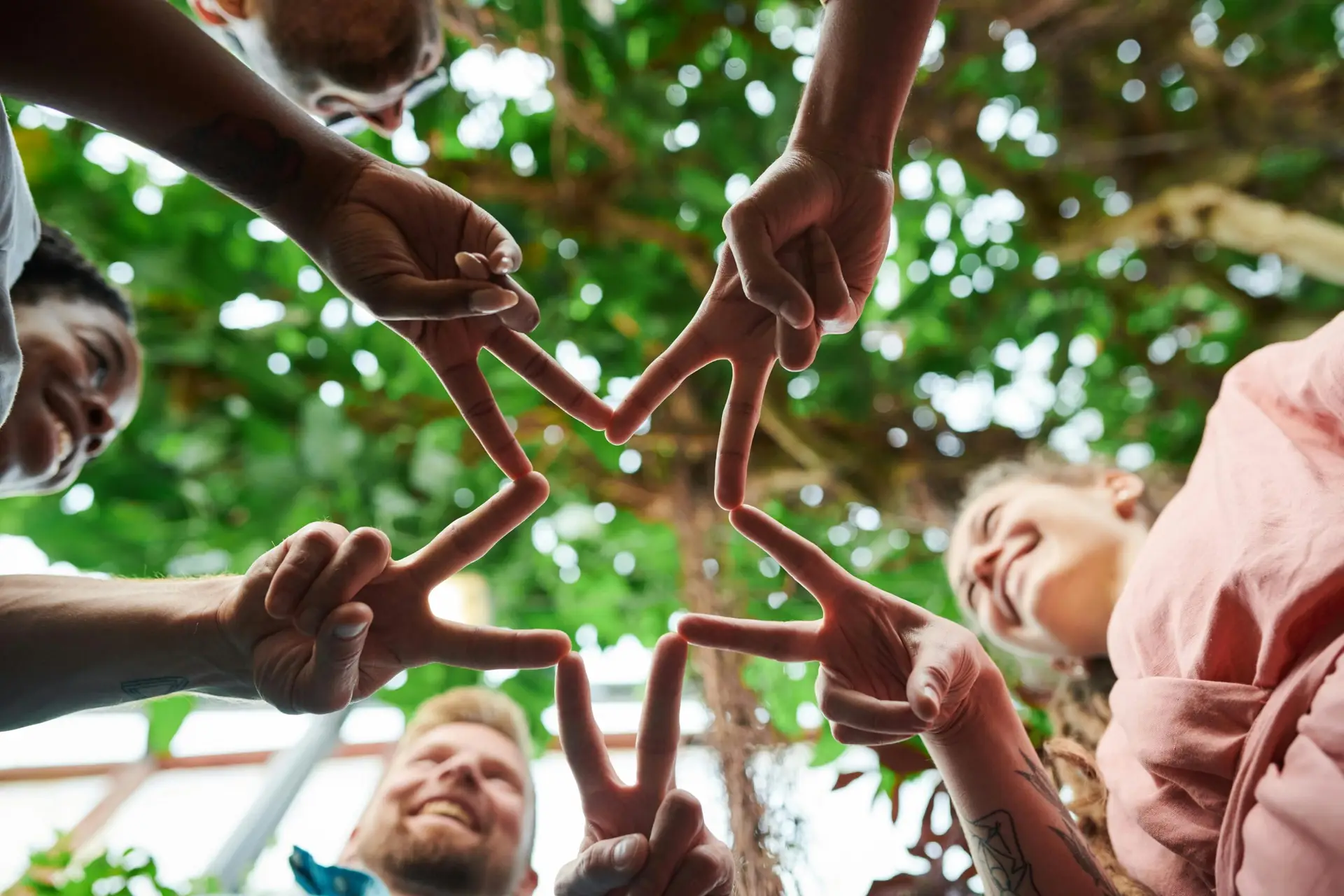 Group of diverse friends forming a star shape with their hands in an outdoor setting.