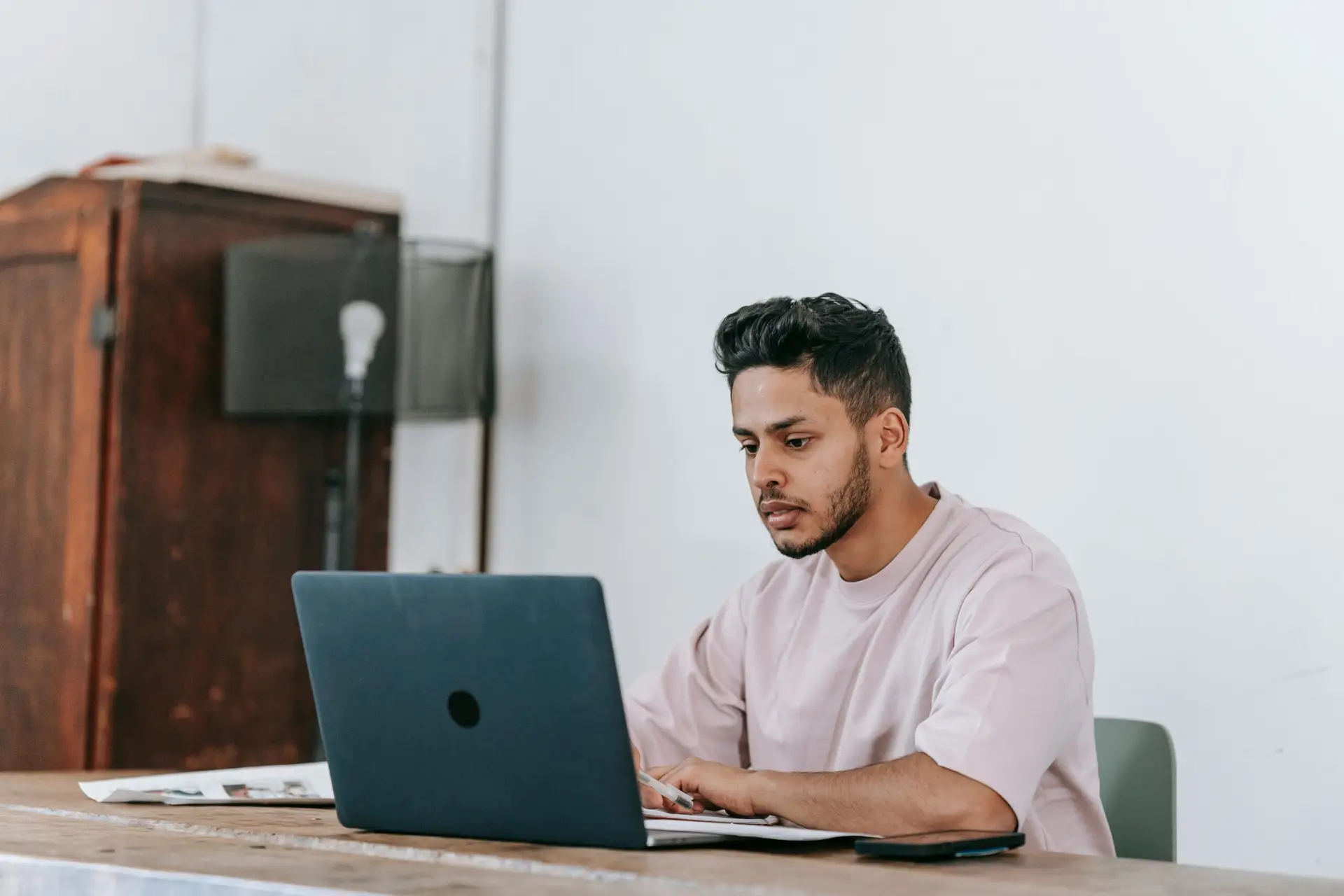 Focused young man working on a laptop in a minimalist home office setting.